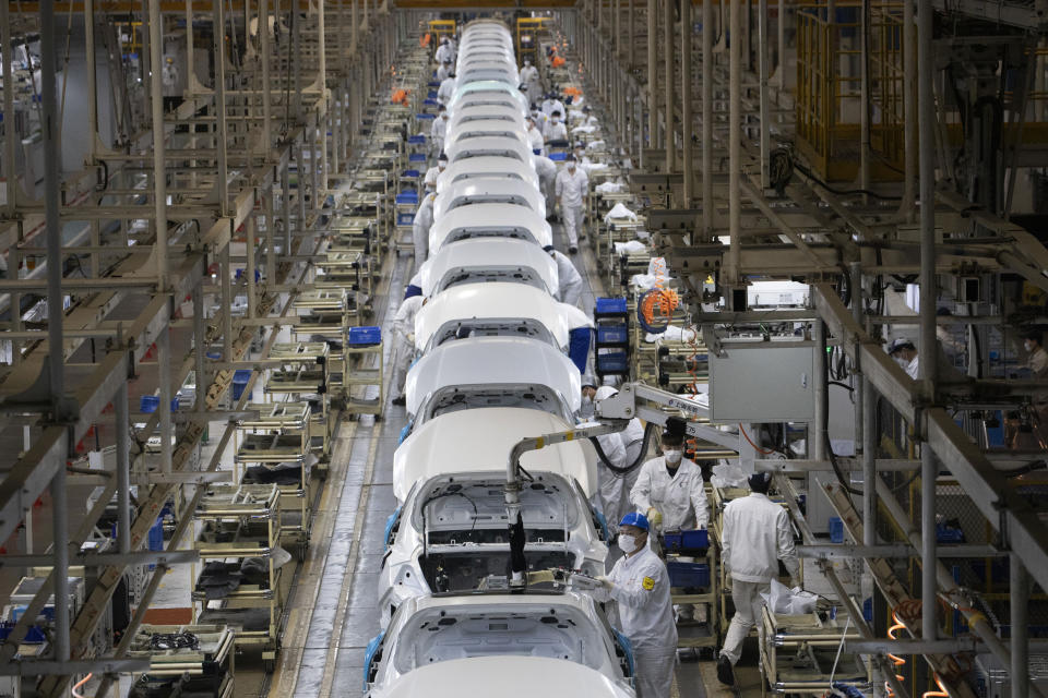 In this April 8, 2020, photo, employees work on a car assembly line at the Dongfeng Honda Automobile Co., Ltd factory in Wuhan in central China's Hubei province. The United States, Japan and France are prodding their companies to rely less on China to make the world’s smartphones, drugs and other products. But even after the coronavirus derailed global trade, few are willing to give up access to its skilled workers, vast market and efficient suppliers by moving factories closer to home. (AP Photo/Ng Han Guan)