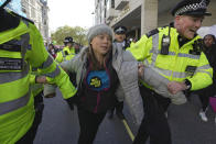 Environmental activist Greta Thunberg is taken away by police officers during the Oily Money Out protest outside the Intercontinental Hostel, in London, Tuesday, Oct. 17, 2023. (AP Photo/Kin Cheung)