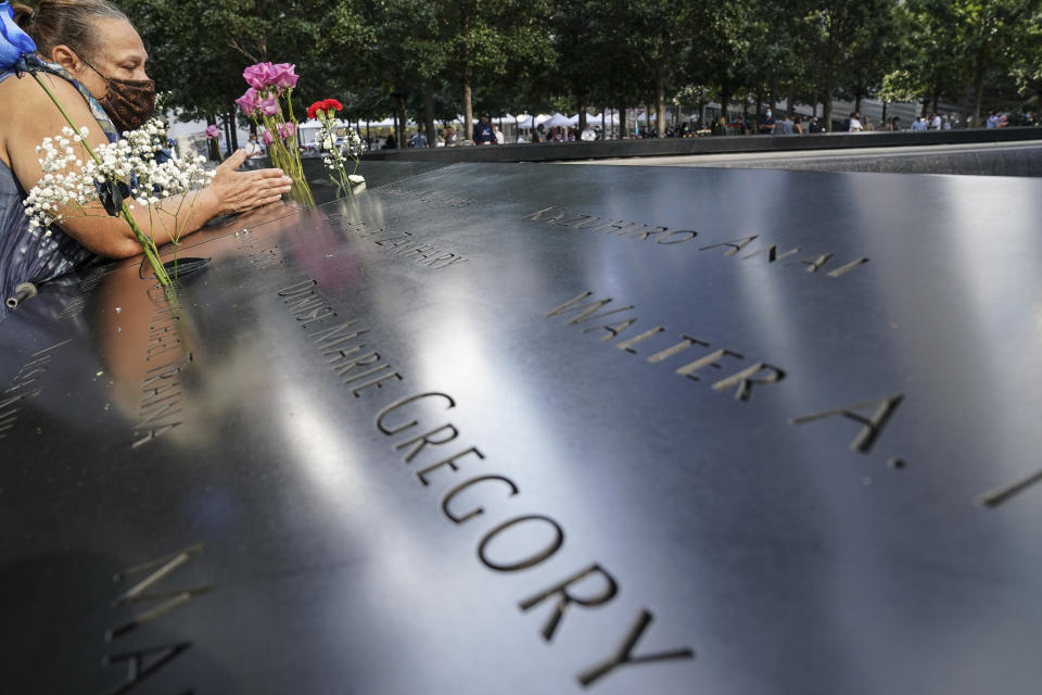 A mourner prays over the inscribed name of the deceased Emilio Pete Ortiz at the National September 11 Memorial and Museum, Friday, Sept. 11, 2020, in New York. (AP Photo/John Minchillo)