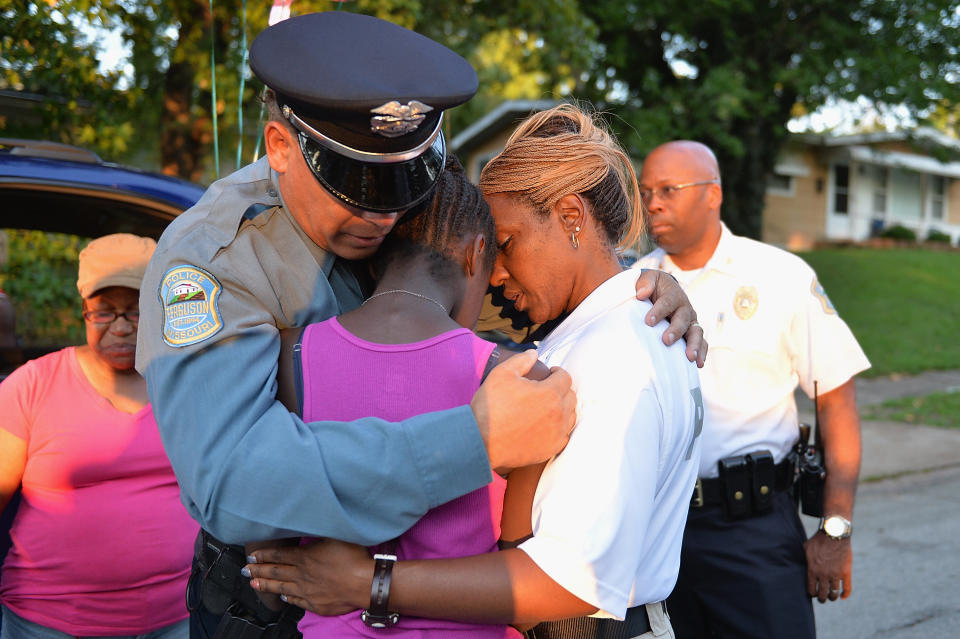 Police officers&nbsp;Greg Casem and Dominica Fuller console a child at&nbsp;a candlelight vigil held in honor of Jamyla Bolden in Ferguson, Missouri. Nine-year-old Jamyla&nbsp;was <a href="http://www.huffingtonpost.com/entry/bullets-fired-into-ferguson-home-kill-9-year-old-girl_55d4fe66e4b07addcb457341">killed in her bed</a>&nbsp;on Aug. 19 when someone fired several rounds into her home.