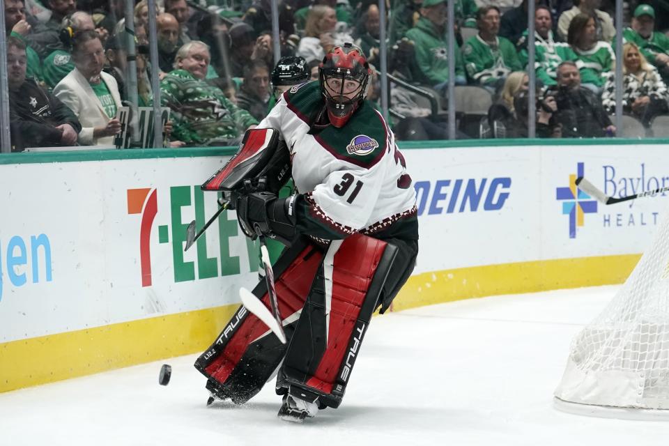 Arizona Coyotes goaltender Scott Wedgewood (31) clears the puck from behind the net under pressure from Dallas Stars center Tanner Kero, rear, in the first period of an NHL hockey game in Dallas, Monday, Dec. 6, 2021. (AP Photo/Tony Gutierrez)