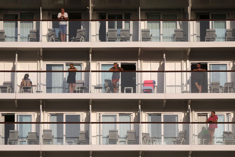 Passengers stand at the balconies of the Mein Schiff 6 cruise ship moored at the dock of Piraeus after some of the crew members tested positive for the coronavirus disease (COVID-19), in Piraeus