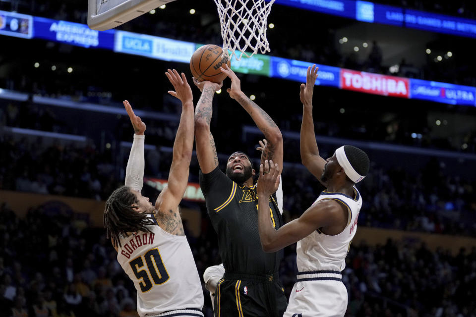 Los Angeles Lakers forward Anthony Davis (3) goes to the basket against Denver Nuggets forward Aaron Gordon (50) and forward Justin Holiday during the first half of an NBA basketball game in Los Angeles, Thursday, Feb. 8, 2024. (AP Photo/Eric Thayer)