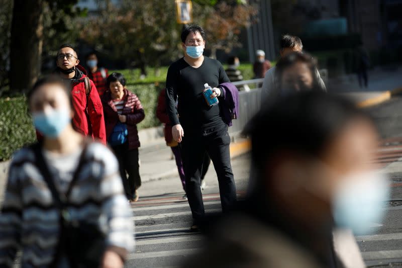 People wearing masks following the coronavirus disease (COVID-19) outbreak walk across a street, in Beijing