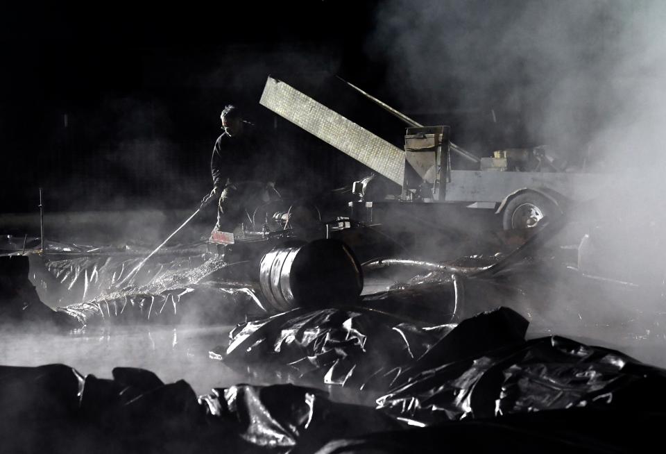 An oil field worker sprays water into one of the pits at the Burger St. drill site Jan. 3. The pits were lined with heavy plastic to contain the water used in the oil drilling process.