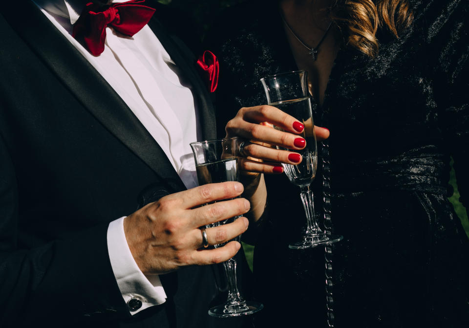 Two people in formal attire toasting with champagne glasses