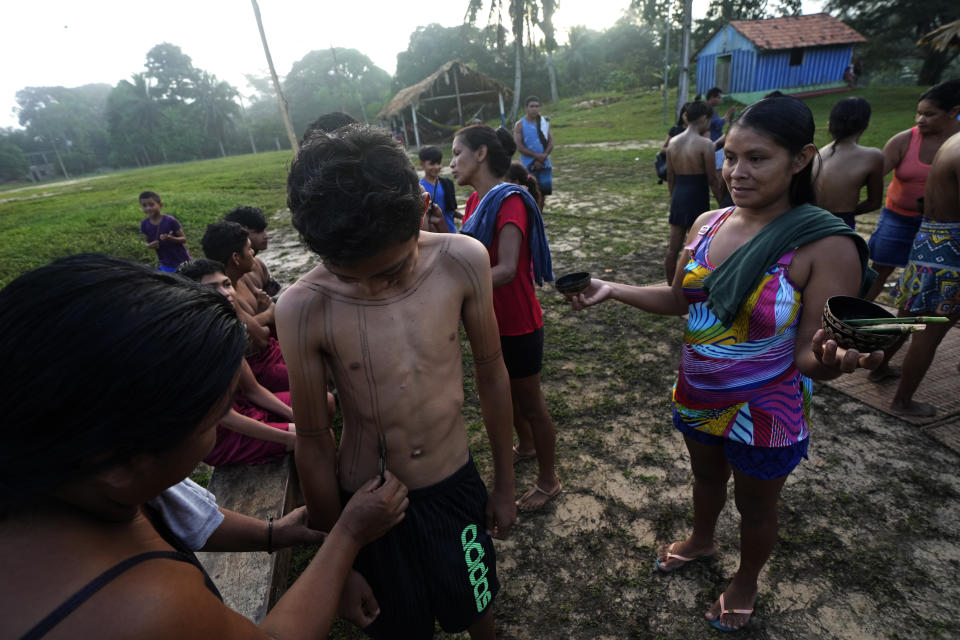 A boy watches as his body is painted with Jenipapo, a traditional Indigenous body paint, on the dawn of the second day of the Wyra'whaw coming-of-age festival in the Ramada ritual center, in Tenetehar Wa Tembe village, located in the Alto Rio Guama Indigenous territory in Para state, Brazil, Saturday, June 10, 2023. Known as the Menina Moca in Portuguese, the three-day festival is for adolescent boys and girls in Brazil's Amazon. (AP Photo/Eraldo Peres)