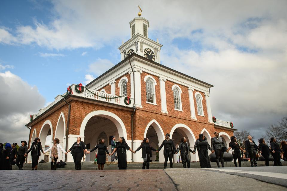 Black women stand around the entire Market House during the 100 Professional Black Women in Black Photo Shoot in downtown Fayetteville on Saturday, Jan. 6, 2024.