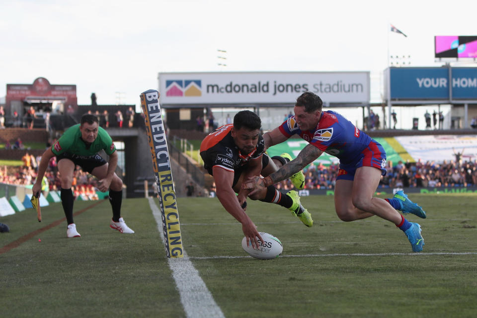 NEWCASTLE, AUSTRALIA - MARCH 28: David Nofoaluma of the Tigers scores a try defended by Kurt Mann of the Knights during the round three NRL match between the Newcastle Knights and the Wests Tigers at McDonald Jones Stadium on March 28, 2021, in Newcastle, Australia. (Photo by Ashley Feder/Getty Images)