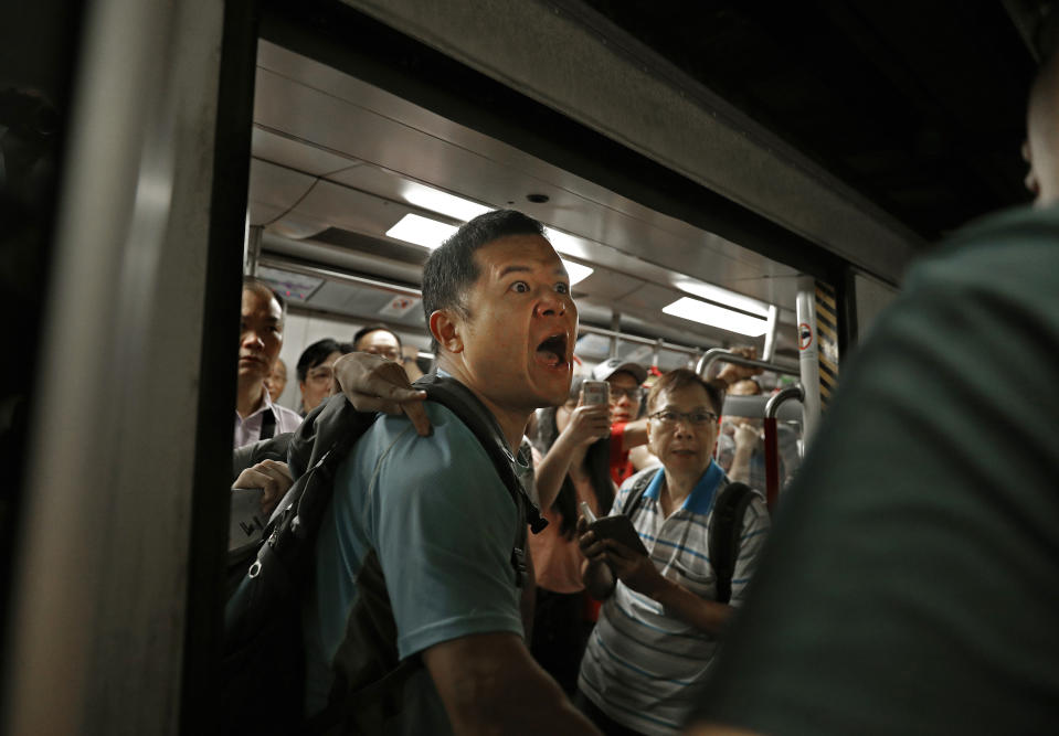 A passenger reacts after protesters blocked the train doors stopping the trains leaving at a subway platform in Hong Kong Wednesday, July 24, 2019. Subway train service was disrupted during morning rush hour after dozens of protesters staged what they called a disobedience movement to protest over a Sunday mob attack at a subway station. (AP Photo/Vincent Yu)