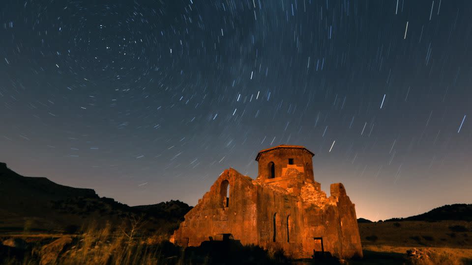 A long exposure photo shows the Perseid meteor shower over Red Church and Guzelyurt Monastery Valley in Turkey on August 12, 2023. - Aytug Can Sencar/Anadolu Agency/Getty Images