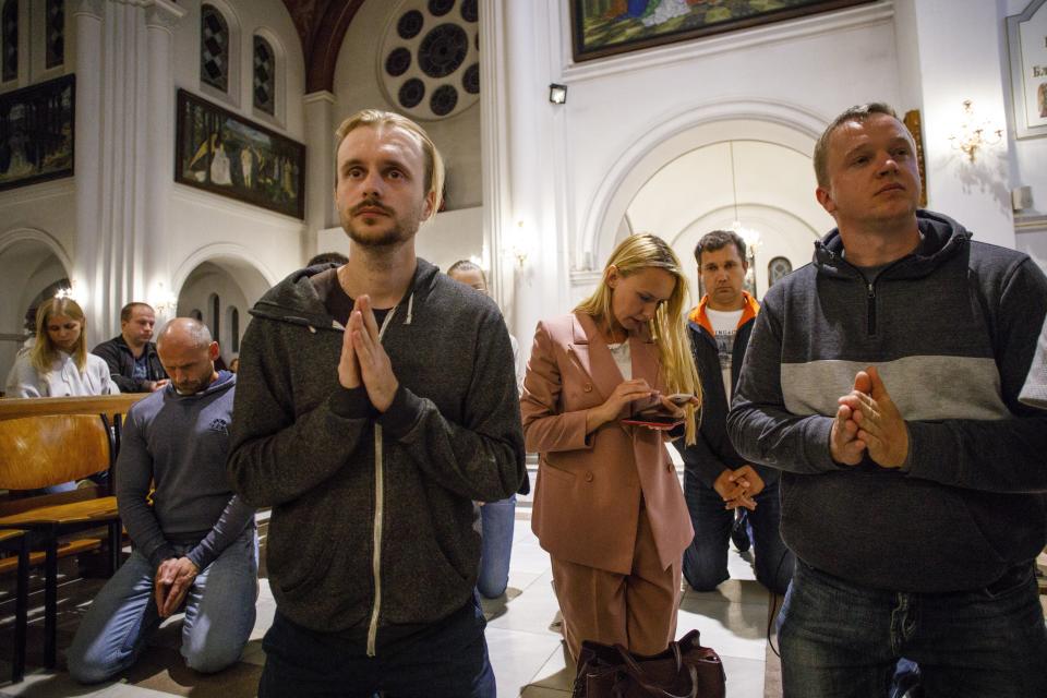 People pray inside a Catholic church in Minsk, Belarus, Wednesday, Aug. 26, 2020. Several dozen protesters found refuge in a Catholic church facing the square, and police blocked its doors to keep them inside while they moved to disperse the demonstration. Minsk Bishop Jury Kasabucki condemned the police action as a violation of freedom of conscience and religion and an insult to believers. Police in Belarus have dispersed protesters who gathered on the capital's central square, detaining dozens. (AP Photo/Dasha Sapranetskaya )