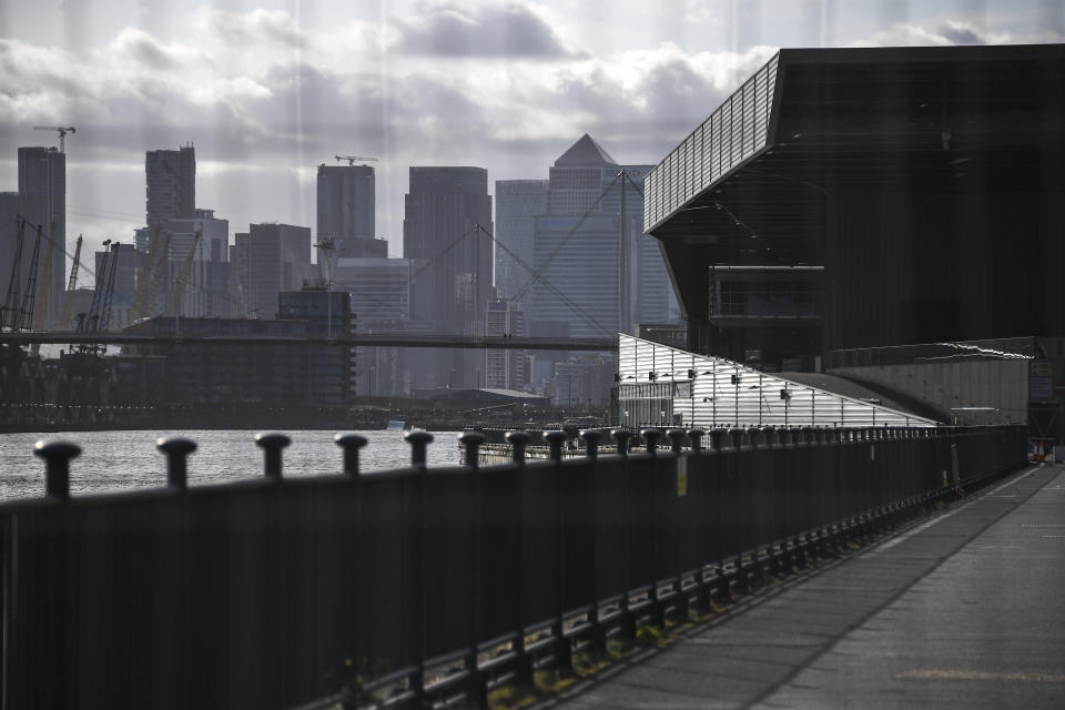 General view of the Canary Wharf skyline and the silhouette of the Excel in London, Saturday, March 28, 2020. The British Government announced Tuesday, that the ExCel Center in east London will become a 4,000 bed temporary hospital to deal with future coronavirus patients, to be called NHS Nightingale. The new coronavirus causes mild or moderate symptoms for most people, but for some, especially older adults and people with existing health problems, it can cause more severe illness or death.(AP Photo/Alberto Pezzali)