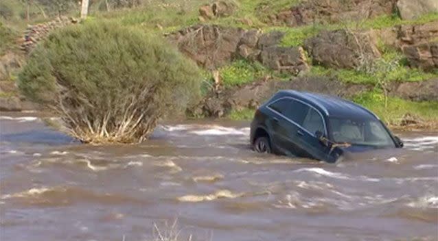 The car is half-submerged by floodwater. Source: 7 News
