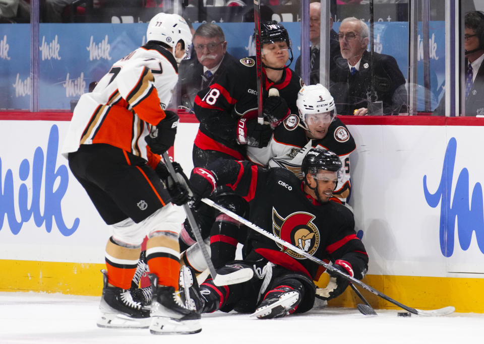 Ottawa Senators center Tim Stutzle (18) and right wing Mathieu Joseph, lower right, pile up on the boards with Anaheim Ducks defenseman Urho Vaakanainen (5) during first-period NHL hockey game action in Ottawa, Ontario, Thursday, Feb. 15, 2024. (Sean Kilpatrick/The Canadian Press via AP)