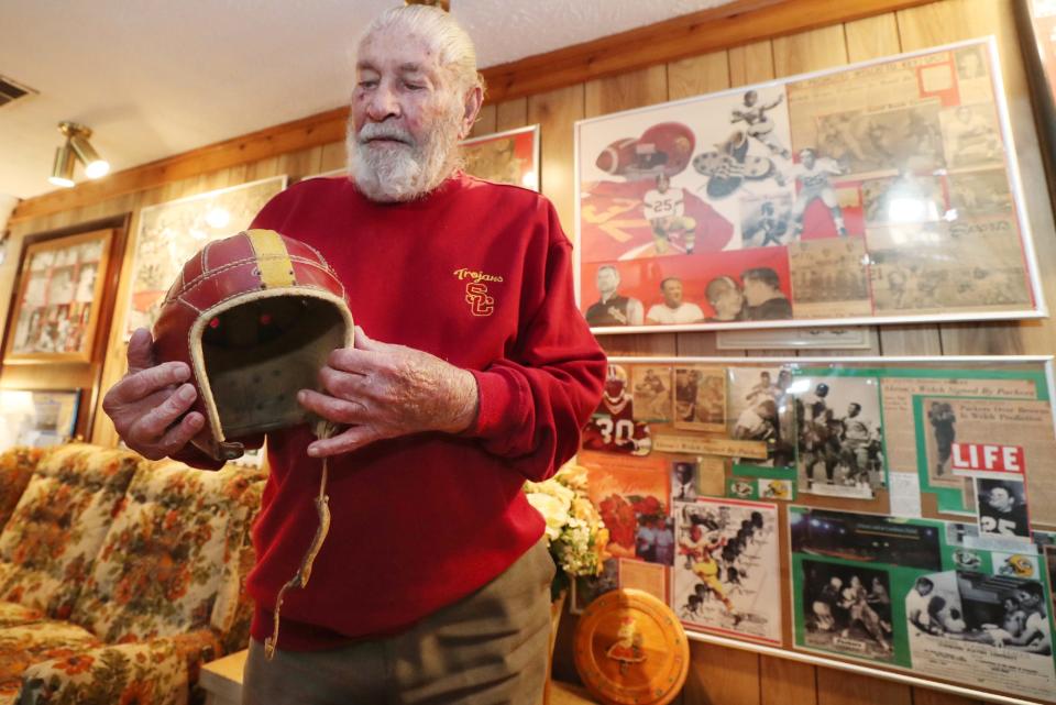 Harry Welch, 92, holds a leather football helmet in the basement of his Green home. An Akron native, Welch competed in the 1953 Rose Bowl, and the helmet is from his days playing football for the University of Southern California.