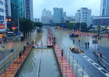 People walk on makeshift walking paths along a flooded street as Typhoon Megi hits Fuzhou, Fujian province, China, September 28, 2016. Picture taken September 28, 2016. REUTERS/Stringer