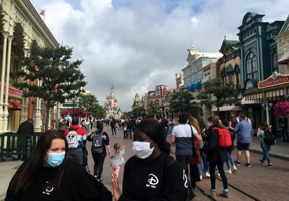 Visitors wearing protective face masks, walk down the Main Street of Disneyland Paris in Marne-la-Vallee, near Paris, on July 15, 2020, as Disneyland Paris begins phased reopening after months-closure aimed at stemming the spread of the novel coronavirus (COVID-19). (Photo by Aurelia MOUSSLY / AFP) (Photo by AURELIA MOUSSLY/AFP via Getty Images)