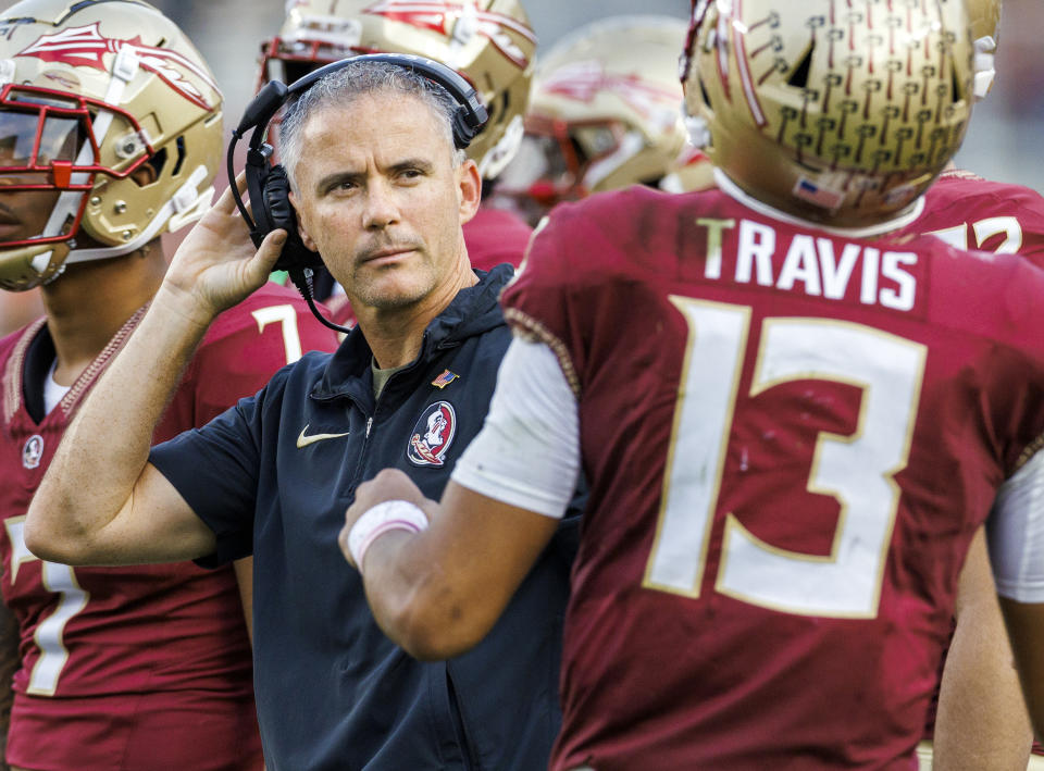 FILE - Florida State head coach Mike Norvell listens to Florida State quarterback Jordan Travis (13) during the first half of an NCAA college football game against Miami Nov. 11, 2023, in Tallahassee, Fla. Norvell has been selected by The Associated Press as the coach of the year for the Atlantic Coast Conference. (AP Photo/Colin Hackley, File)