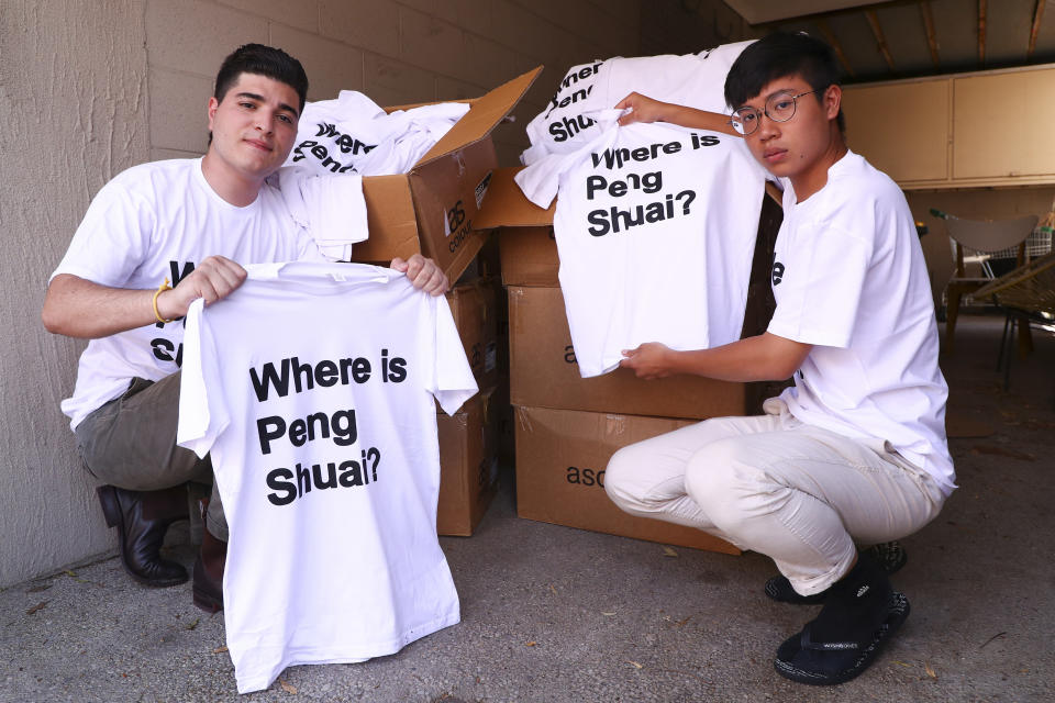 Drew Pavlou, left, and Max Mok show some of the 1,000 shirts they plan to hand out to patrons ahead of Saturday's women's singles final at the Australian Open tennis championships in Melbourne, Australia, Friday, Jan. 28, 2022. As he was being ejected for wearing a shirt with a Where is Peng Shuai? slogan, Max Mok saw an opportunity to amplify the message at the Australian Open. (AP Photo/Tertius Pickard)