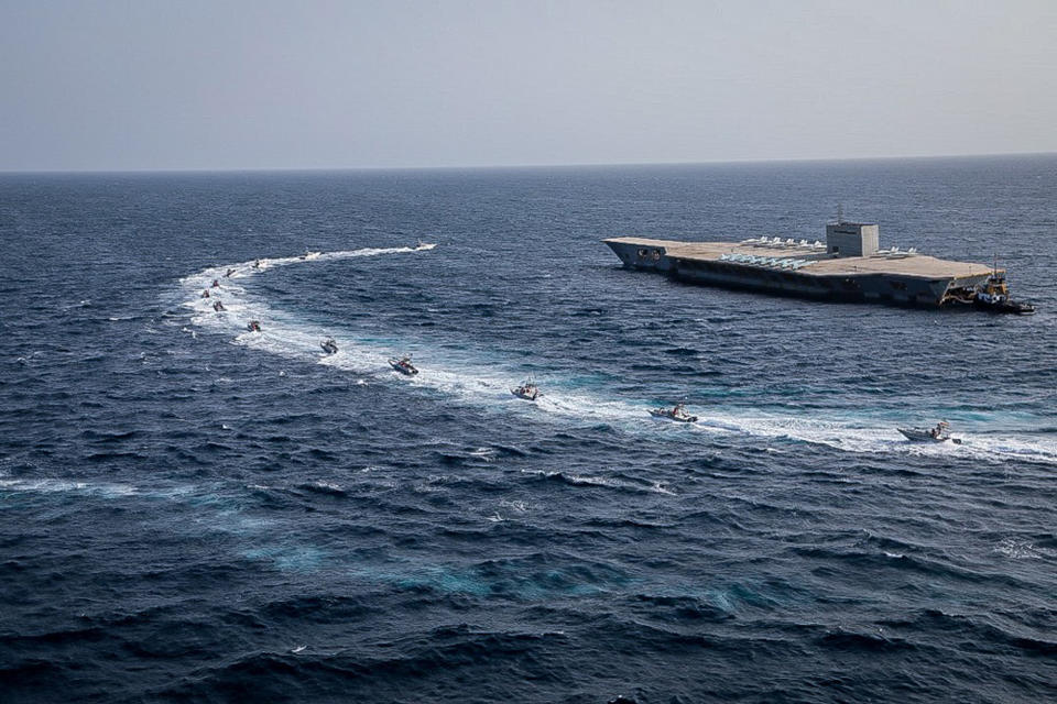 In this photo released Tuesday, July 28, 2020, by Sepahnews, Revolutionary Guard's speed boats circle around a replica aircraft carrier during a military exercise. Iran's paramilitary Revolutionary Guard has fired a missile from a helicopter targeting the mock-up aircraft carrier in the strategic Strait of Hormuz according to footage aired on state television on Tuesday. Iranian commandos also fast-roped down from a helicopter onto the replica in the footage from the exercise called "Great Prophet 14." The drill appears aimed at threatening the U.S. amid tensions between Tehran and Washington. (Sepahnews via AP)