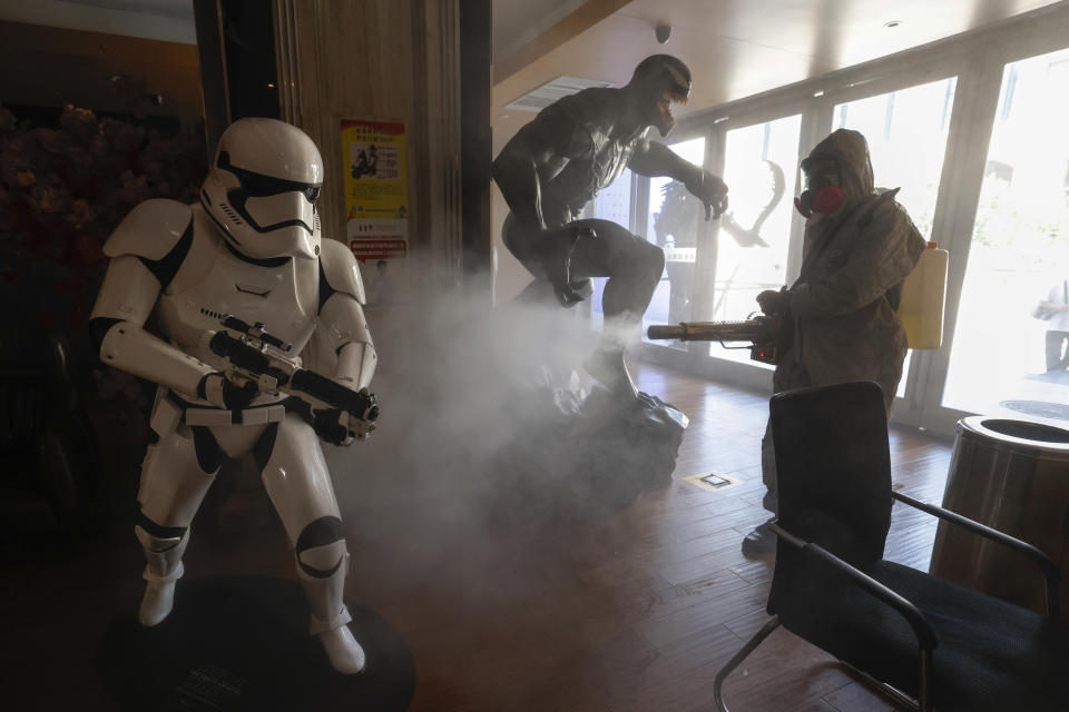 Volunteers with the Blue Sky Rescue team perform disinfecting of a cinema before it reopens for business in Beijing Friday, July 24, 2020. Theaters in China, the world's second largest movie market, this week reopened from the coronavirus shut down with theaters limited to 30% capacity. (AP Photo/Ng Han Guan)