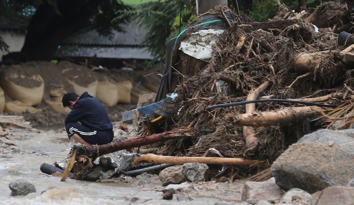 A man sits next to his collapsed house after a landslide caused by heavy rain in Yecheon, South Korea (AP)