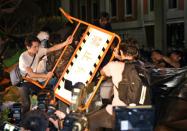 Protesters use a barricade to push down a barbed wire fence as they cross over the fence into the Education Ministry during a demonstration in Taipei early on July 31, 2015