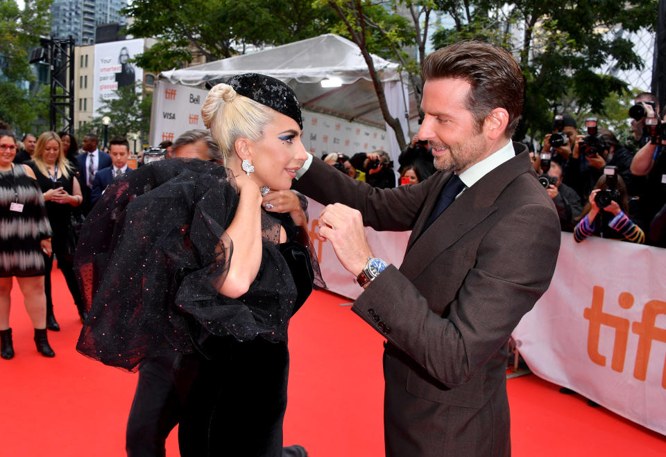 He’s even a good date. Bradley Cooper assists Lady Gaga with a wardrobe malfunction at the<em> A Star Is Born</em> premiere at the 2018 Toronto International Film Festival on Sept. 9. (Photo: Getty Images)