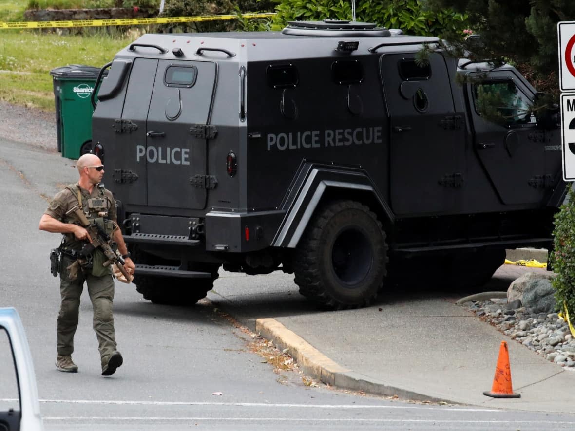 A police officer looks on after two armed men were killed in a shootout with the police in Saanich, B.C., on Tuesday. (Kevin Light/REUTERS - image credit)