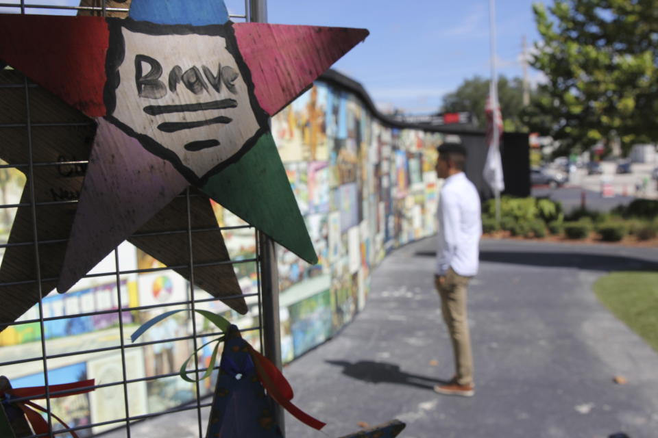 Brandon Wolf, a survivor of the Pulse nightclub shooting and activist, looks at the photos that are a part of the Pulse memorial in Orlando, Fla., on Sept. 9, 2022. After mass shootings, the loss felt by marginalized groups already facing discrimination is compounded. Some public health experts say the risk for post-traumatic stress disorder is greater for the groups, especially when the shootings take place at schools, churches and other vital hubs. (AP Photo/Cody Jackson)