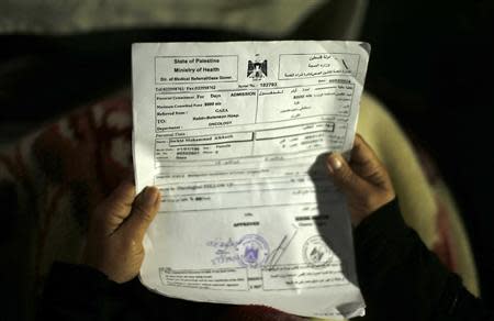 Suhad al-Katib, a Palestinian woman patient who suffers cancer holds paperwork inside her house after she was not allowed to enter Israel, in Gaza City February 12, 2014. REUTERS/Mohammed Salem