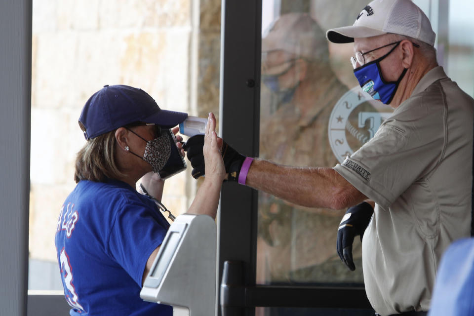 Amid concerns of the spread of the virus that causes COVID-19, a baseball fan has their temperature checked by a security guard before being allowed to tour Globe Life Field, home of the Texas Rangers baseball team in Arlington, Texas, Monday, June 1, 2020. The coronavirus pandemic has forced sports teams and their leagues to evaluate how they will welcome back fans. (AP Photo/LM Otero)