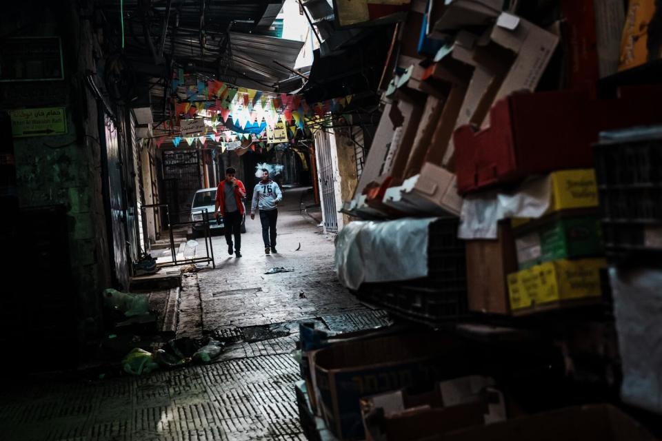 People walking past shuttered stores in the Old City of Nablus, West Bank