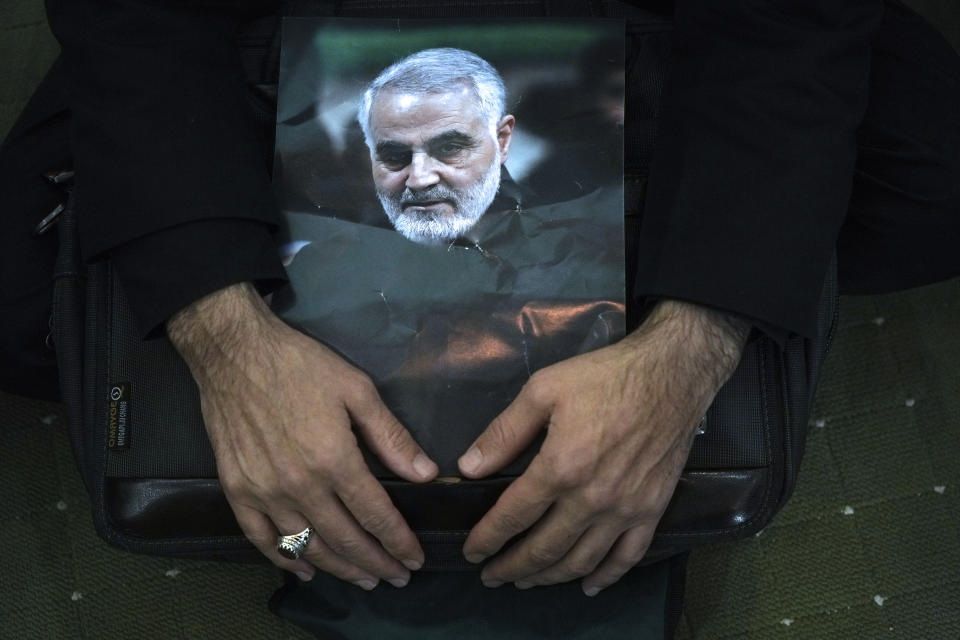 A mourner holds a poster of the late Revolutionary Guard Gen. Qassem Soleimani, who was killed in Iraq in a U.S. drone attack in 2020, during a ceremony marking anniversary of his death, at Imam Khomeini Grand Mosque in Tehran, Iran, Tuesday, Jan. 3, 2023. Iran's President Ebrahim Raisi on Tuesday vowed to avenge the killing of the country's top general on the third anniversary of his death, as the government rallied its supporters in mourning amid months of anti-government protests. (AP Photo/Vahid Salemi)