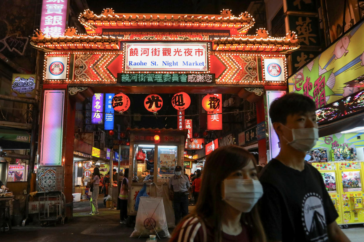 People wear a face mask to prevent the spread of the coronavirus disease (COVID-19) while passing a night market in Taipei, Taiwan, August 6, 2020. REUTERS/Ann Wang