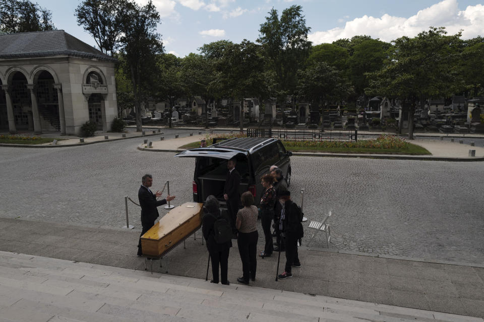 Paris undertaker Franck Vasseur of L'autre rive funeral directors, left, comforts family members during a funeral ceremony at Pere Lachaise cemetery in Paris, Friday, April 24, 2020 as a nationwide confinement continues to counter the COVID-19 virus. In lockdown, Vasseur says his job became "completely different," a procession of death, disposal and paperwork, of days spent shuttling bodies from A to B, of waiting in line with other hearses and dealing by phone and email with locked-down families he could no longer comfort in person.(AP Photo/Francois Mori)