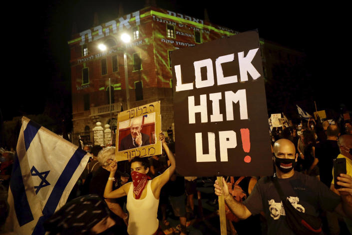 Israeli protesters hold signs and chant slogans during a demonstration against Israeli Prime Minister Benjamin Netanyahu near the Prime Minister's residence in Jerusalem, Sunday, Sept. 20, 2020. (AP Photo/Sebastian Scheiner)