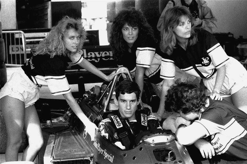 FILE - In this April 11, 1986, file photo, Brazilian driver Ayrton Senna concentrates before time trials for Sunday's Spanish Grand Prix as John Player publicity girls surround his Lotus-Renault. Senna finished first in the trials. Brazil’s adoration of Ayrton Senna transcends sports. Senna won three Formula One titles — in 1988, 1990 and '91 — all with McLaren. He moved to the Williams team for his tragic 1994 season. Despite his career being cut short when he was 34, his 41 wins stand third all-time behind Michael Schumacher's 91 and rival Alain Prost's 51. He died at the 1994 San Marino Grand Prix. (AP Photo/Ricardo, File)