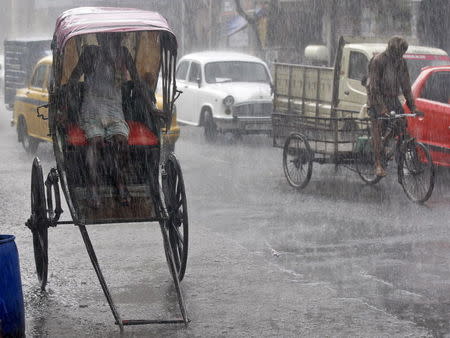 A man takes shelter inside his rickshaw during a heavy rain shower in Kolkata, June 25, 2015. REUTERS/Rupak De Chowdhuri