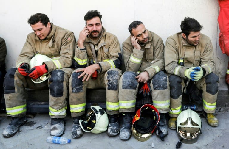 Iranian emergency personnel mourn for lost colleagues and friends on January 20, 2017 as they sit in front of the wreckage of the 15-storey Plasco building in the capital Tehran which collapsed the previous day