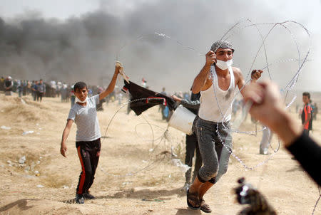 Palestinian demonstrators carry part of the Israeli barbed wire they removed during clashes with Israeli troops at a protest demanding the right to return to their homeland, at the Israel-Gaza border, east of Gaza City, April 13, 2018. REUTERS/Mohammed Salem