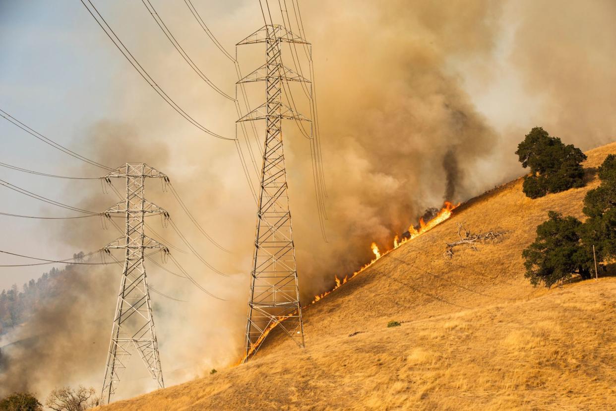 A back fire set by fire fighters burns a hillside behind PG&E; power lines during firefighting operations to battle the Kincade Fire in Healdsburg, Calif. on October 26, 2019.