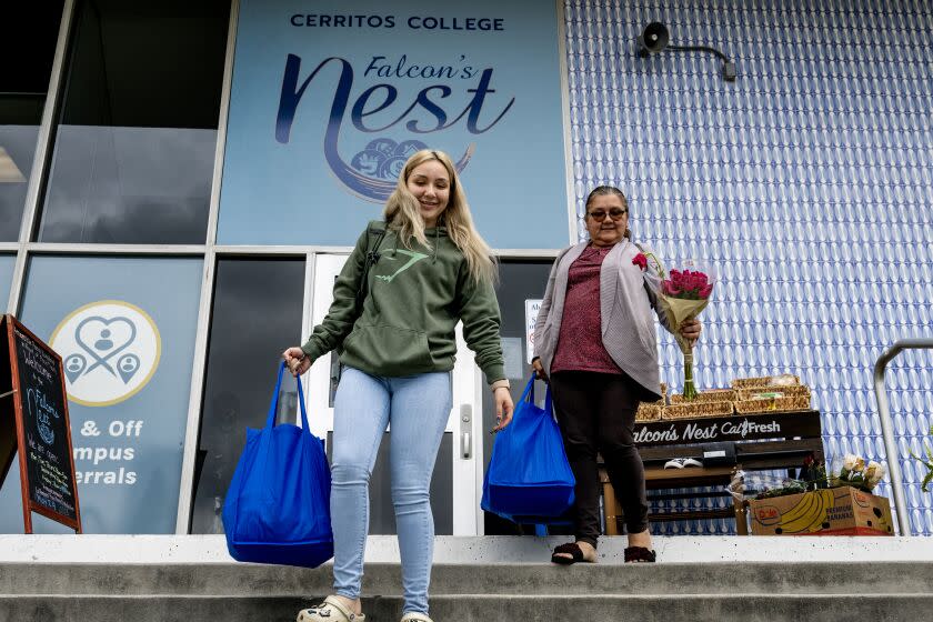 CERRITOS, CA - MAY 9, 2023: Criminal Justice student Maryleen Ramos, 20, left, with her mom Martha's help, carries free groceries from the Falcon's Nest, a free food and clothing pantry, at Cerritos College on May 9, 2023 in Cerritos, California. The college is in dire need of affordable student housing and officials there want the grant money funneled to community colleges not the UC and CSU schools. (Gina Ferazzi / Los Angeles Times)