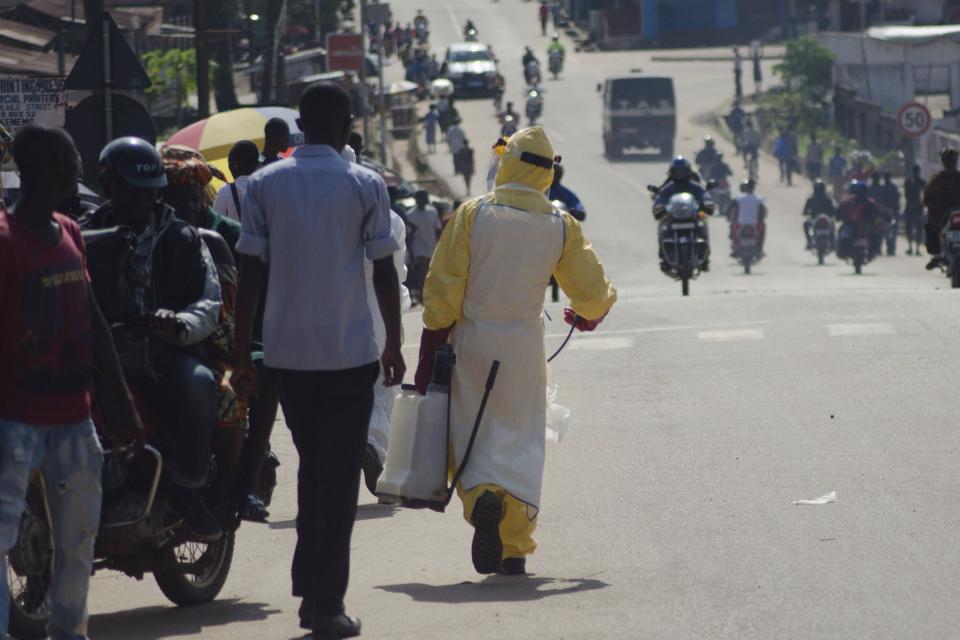 A health worker with disinfectant spray walks down a street outside the government hospital in Kenema, July 10, 2014. Ebola has killed 632 people across Guinea, Liberia and Sierra Leone since an outbreak began in February, putting strain on a string of weak health systems facing one of the world's deadliest diseases despite waves of international help. Picture taken July10, 2014. REUTERS/Tommy Trenchard (SIERRA LEONE - Tags: HEALTH)