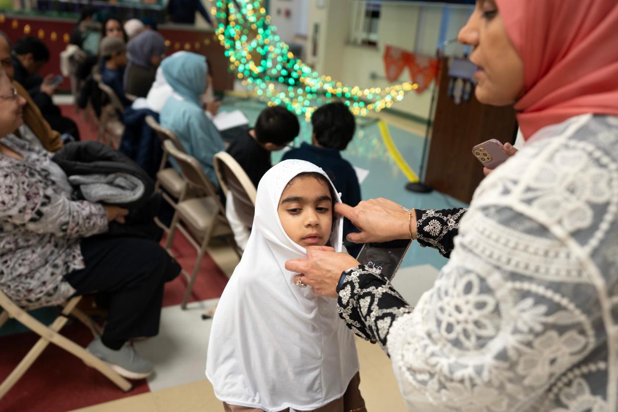 Mar 7, 2024; Teaneck, NJ, USA; Reshma Khan adjusts her daughter Zakia’s hijab during a Ramadan crescent moon lighting at the Rodda Center.