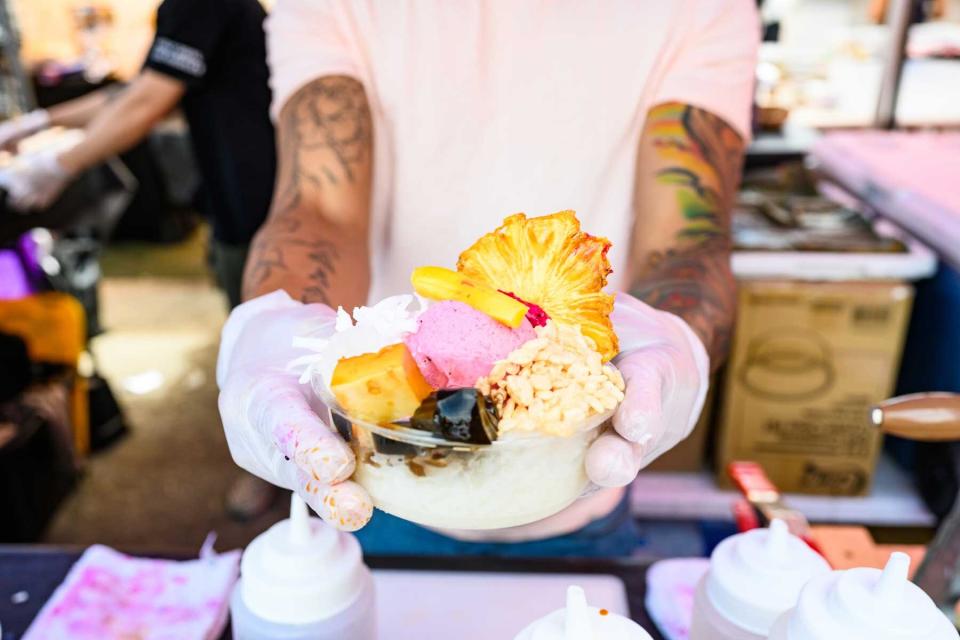 In New York City, United States a working food vendor wearing protective gloves shows a freshly made Philippine dessert at the Smorgasburg food event.