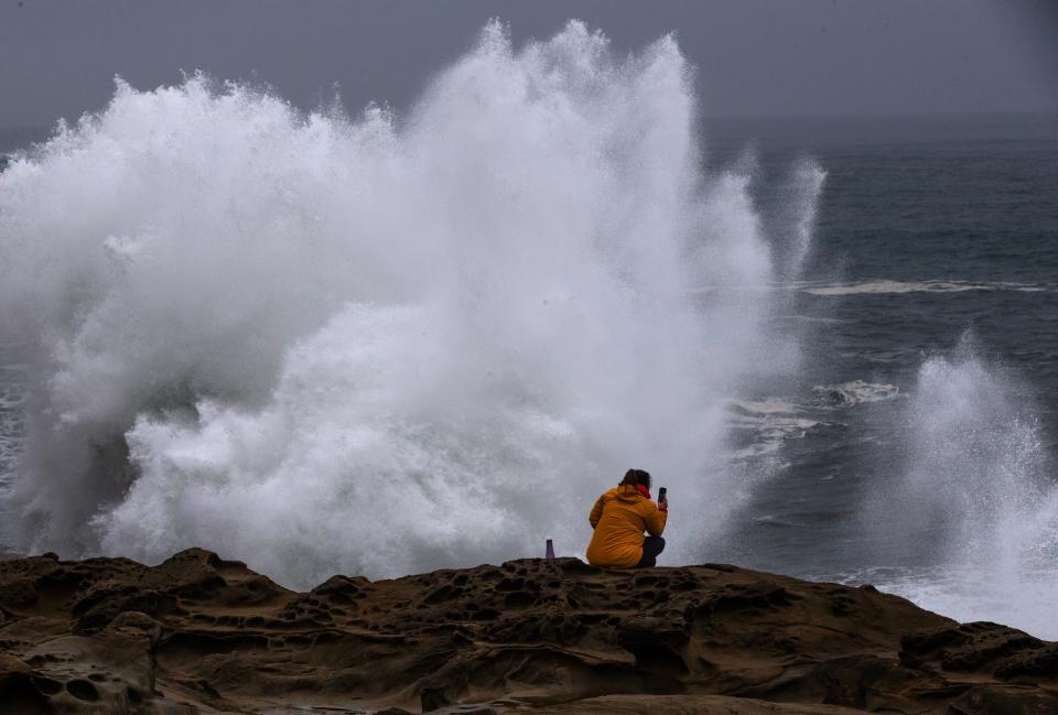 Waves crash on the rocks at Shore Acres State Park on the Oregon Coast during a king tide event on Jan. 22, 2023 as a spectator watches from a safe vantage above.