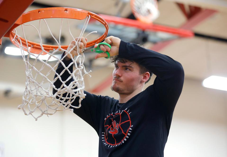 Laingsburg's Elliott Wilsey cuts down his piece of the net after defeating Bath, Tuesday, Feb. 20, 2024, in Mason.