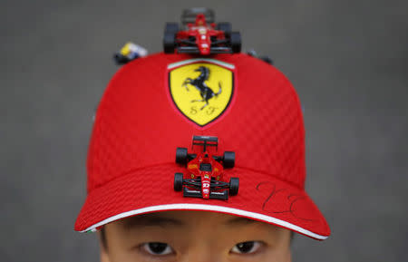 A 10 year old Ferrari fan shows his cap with miniatures of Ferrari's formula one car just after getting an autograph of his favourite driver Kimi Raikkonen of Finland, after the qualifying session of the Japanese F1 Grand Prix at the Suzuka Circuit October 4, 2014. REUTERS/Yuya Shino